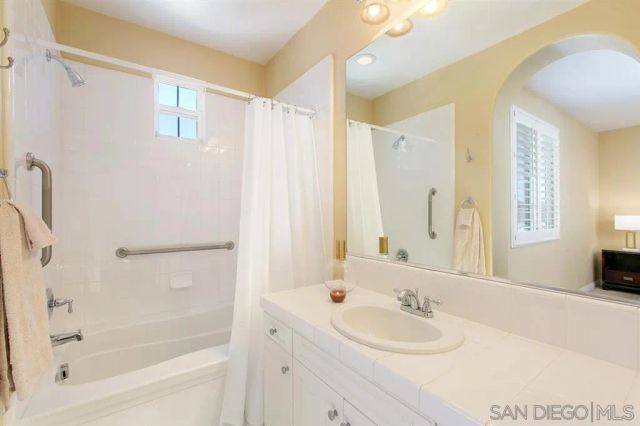 a bathroom with a bathtub shower sink and a mirror