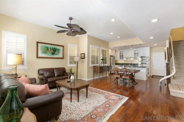 a living room with furniture kitchen view and a wooden floor