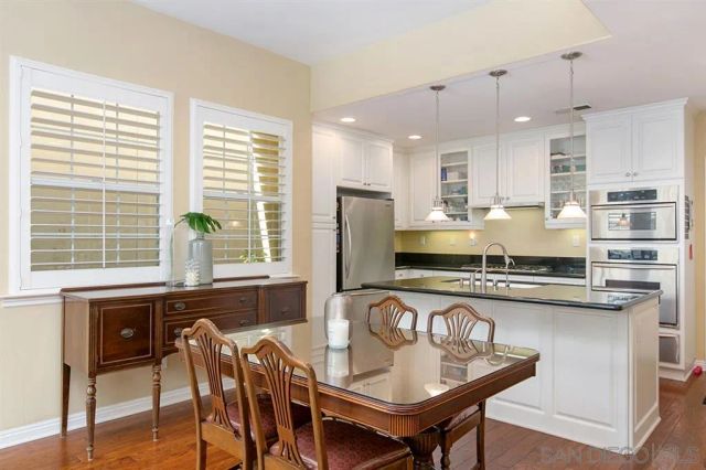 a kitchen with stainless steel appliances granite countertop a stove a refrigerator a sink a dining table and chairs