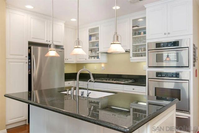 a kitchen with stainless steel appliances granite countertop a sink a stove and a refrigerator
