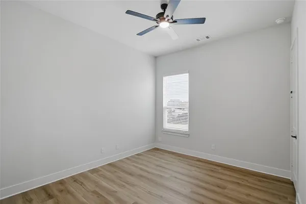 an empty room with wooden floor fan and windows