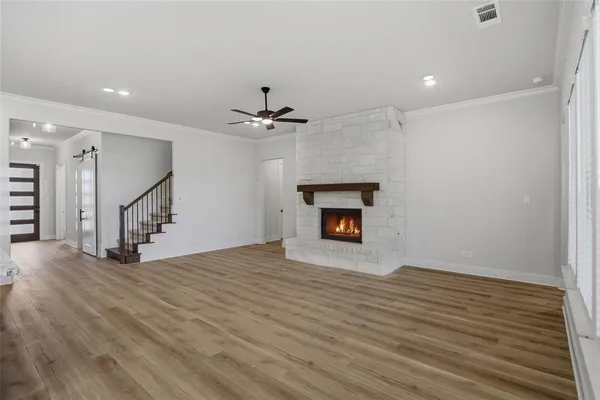 a view of an empty room with wooden floor fireplace and a window