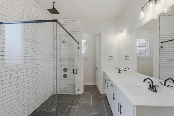 a bathroom with a double vanity sink a large mirror and shower