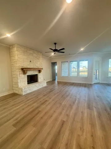 a view of an empty room with wooden floor and a fireplace
