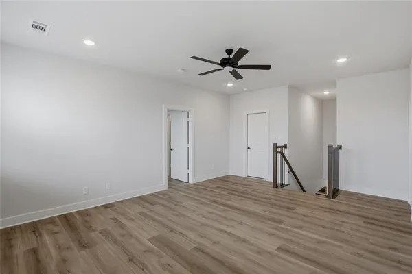 a view of empty room with wooden floor and ceiling fan