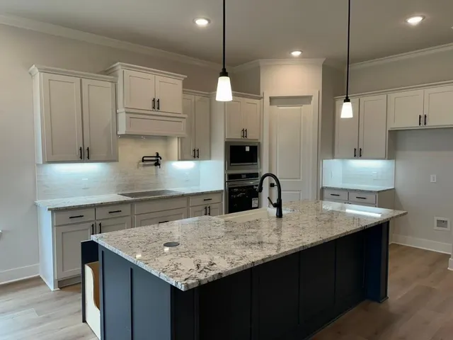a kitchen with kitchen island granite countertop a sink a center island stainless steel appliances and cabinets