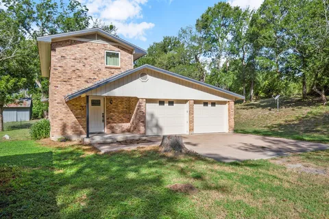 a view of a house with a yard and large tree