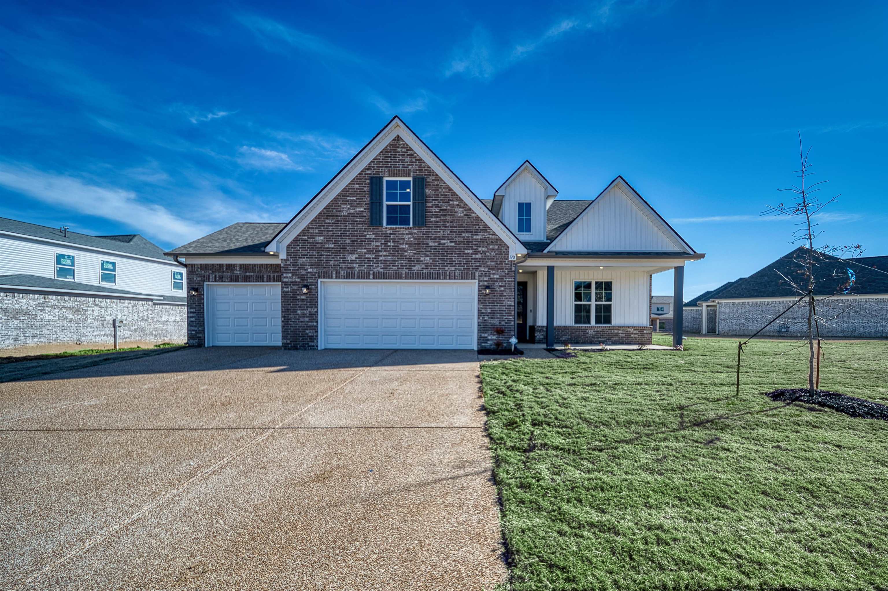 170 Como Lane Atoka, TN 38004 - Photo 1 of 40 View of front of home with a porch, concrete driveway, brick siding, board and batten siding, and an attached garage