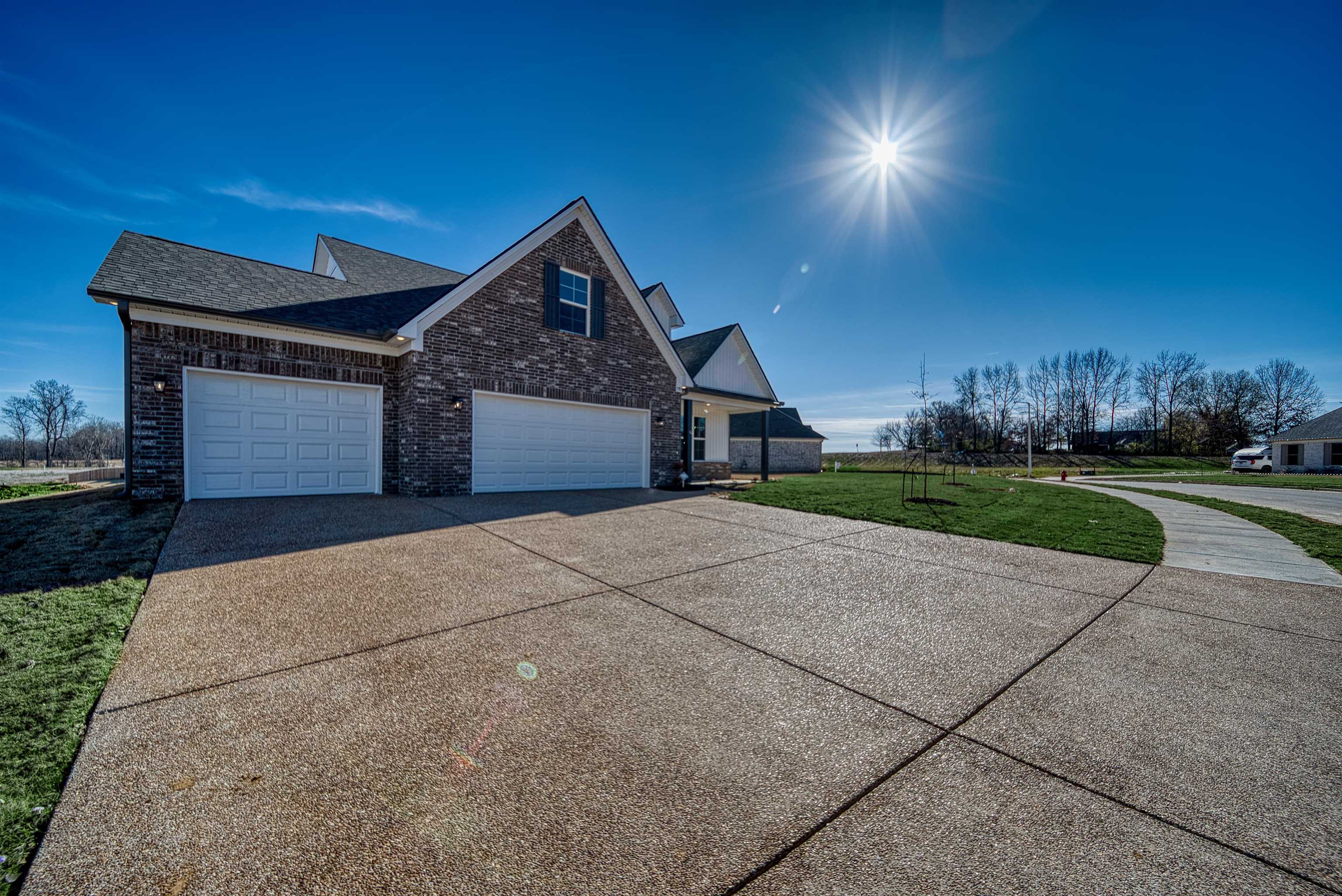 170 Como Lane Atoka, TN 38004 - Photo 37 of 40 View of home's exterior featuring driveway, a yard, brick siding, an attached garage, and a shingled roof