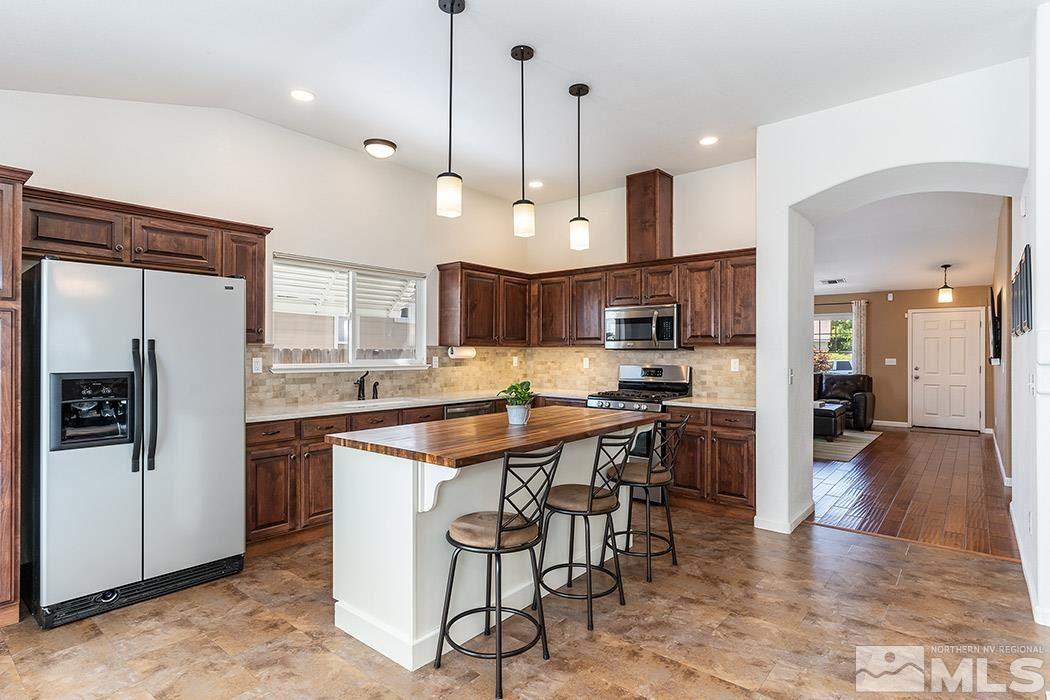 9778 Thunder Mountain Way Reno, NV 89521 - Photo 7 of 21 a kitchen with stainless steel appliances kitchen island a refrigerator and a stove top oven