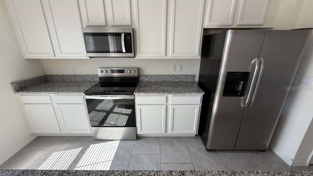17061 Water Spring Boulevard Winter Garden, FL 34787 - Photo 6 of 17 a kitchen with a refrigerator stove and cabinets