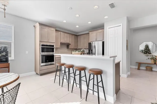 a kitchen with stainless steel appliances granite countertop a table chairs sink and cabinets