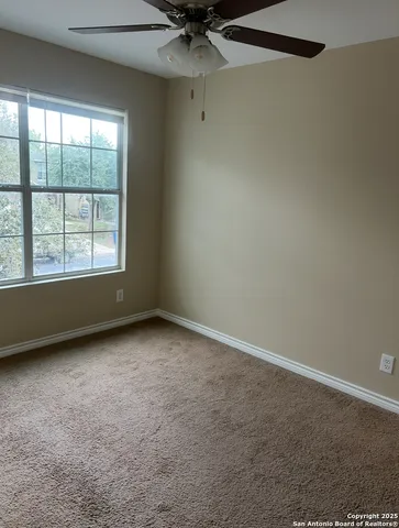 an empty room with a window and a fan