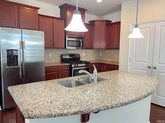 a kitchen with kitchen island granite countertop a sink a counter top space appliances and cabinets