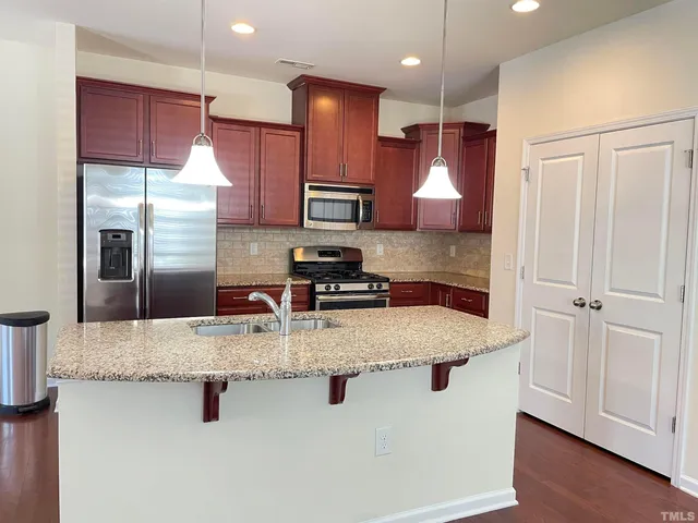 a kitchen with stainless steel appliances granite countertop a sink refrigerator and microwave