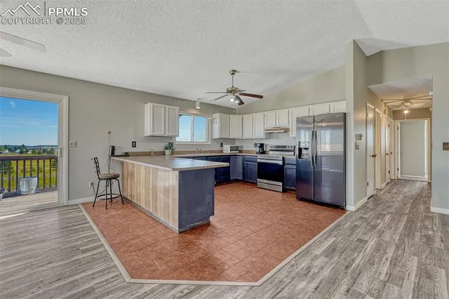 a large kitchen with stainless steel appliances granite countertop a large counter top and wooden floors