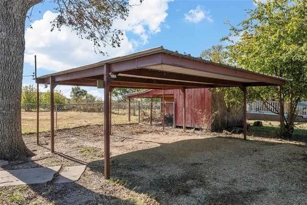 a backyard of a house with a table and chairs under an umbrella