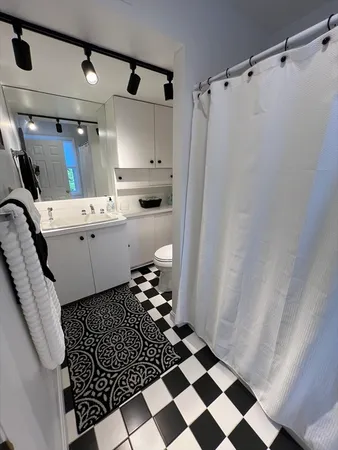 a room with a black white checkered floor with a rug