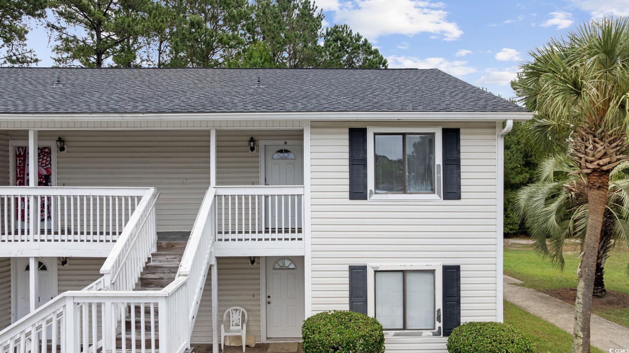 Coastal inspired home with stairway, a shingled roof, and a porch