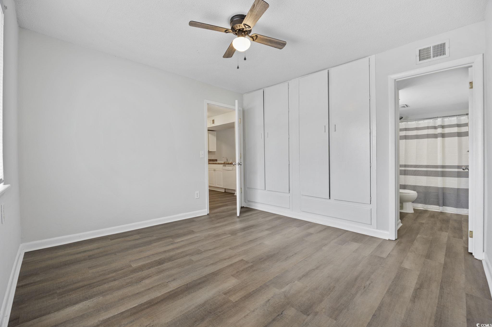 3555 Highway 544, Unit 8H Conway, SC 29526 - Photo 11 of 22 Unfurnished bedroom featuring wood finished floors, connected bathroom, and a ceiling fan