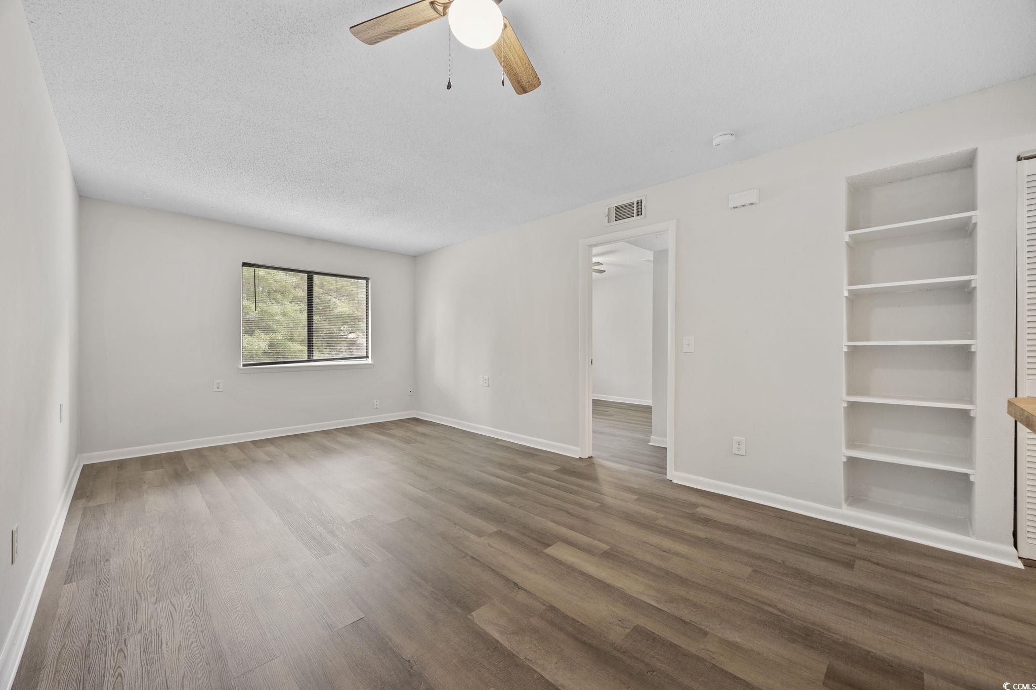3555 Highway 544, Unit 8H Conway, SC 29526 - Photo 17 of 22 Empty room with ceiling fan, dark wood finished floors, a smoke detector, and built in shelves