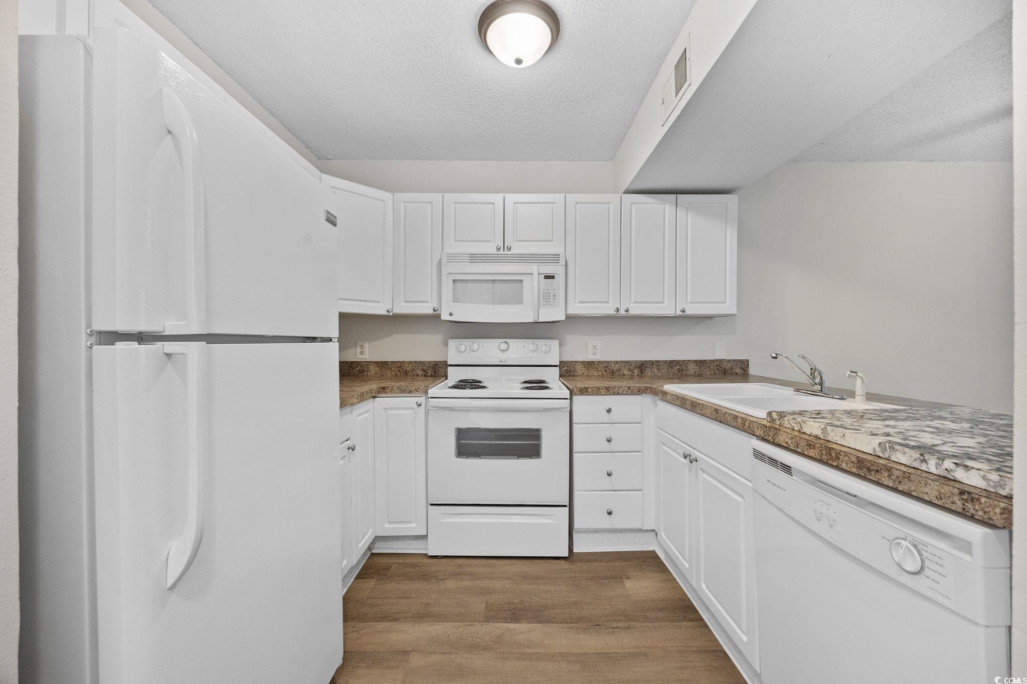3555 Highway 544, Unit 8H Conway, SC 29526 - Photo 7 of 22 Kitchen with white appliances, wood finished floors, white cabinets, and a textured ceiling