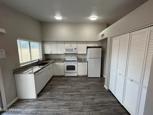 a kitchen with granite countertop white cabinets and white appliances