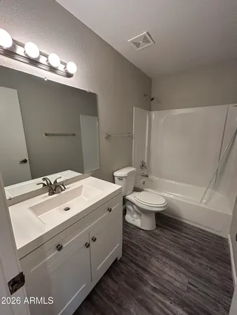 a view of a refrigerator in kitchen and an empty room with wooden floor
