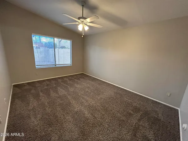an empty room with a chandelier fan and windows