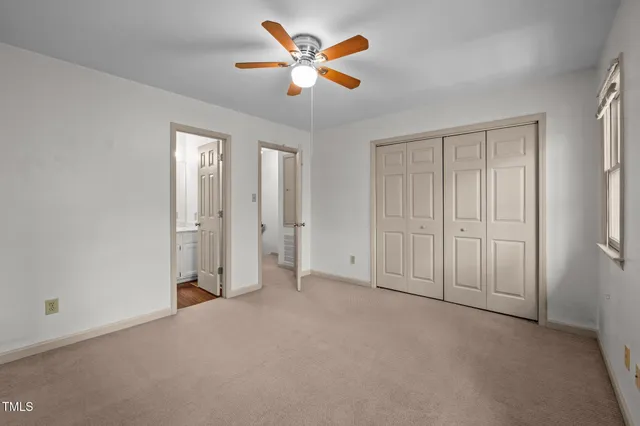 an empty room with closet and a ceiling fan