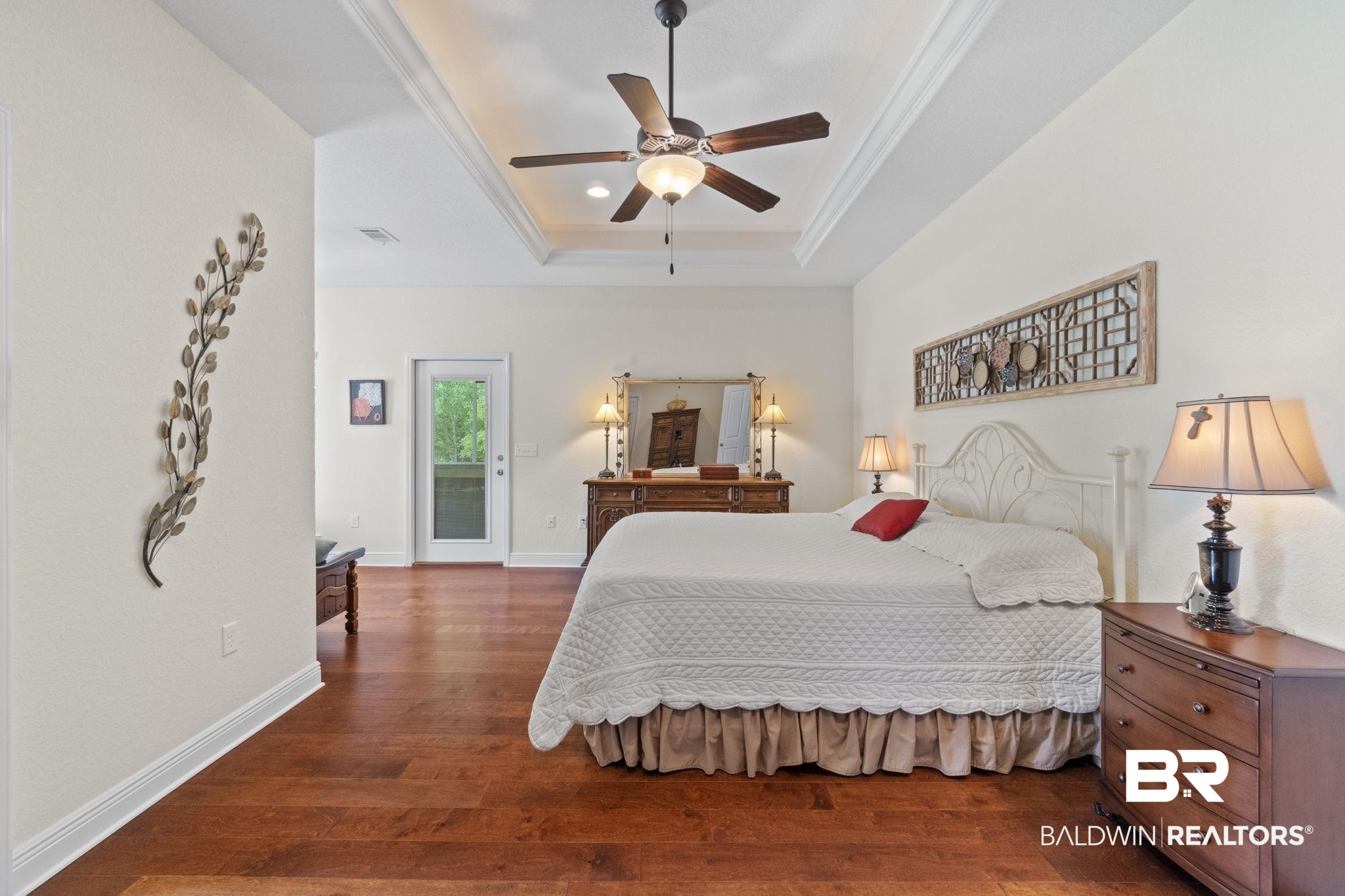 8664 Foxtail Loop Pensacola, FL 32526 - Photo 33 of 64 Bedroom featuring a tray ceiling, dark wood-style flooring, access to exterior, crown molding, and baseboards