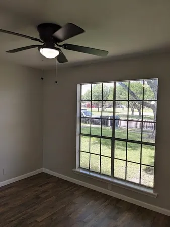 an empty room with wooden floor and windows