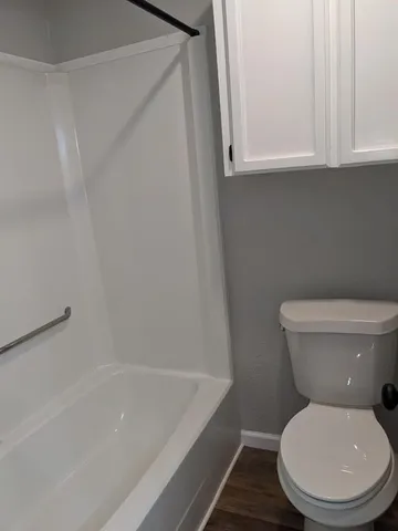 a white toilet sitting next to a bath tub