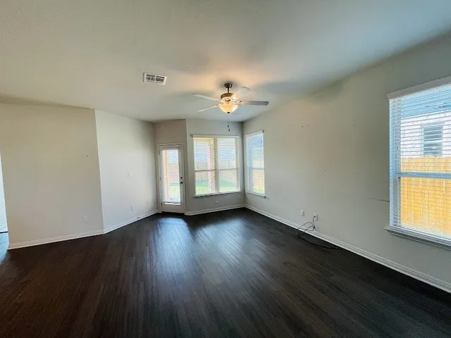 a view of an empty room with wooden floor and a window