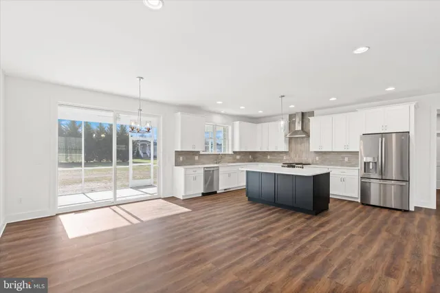 a large kitchen with kitchen island a large counter top a sink stainless steel appliances and cabinets