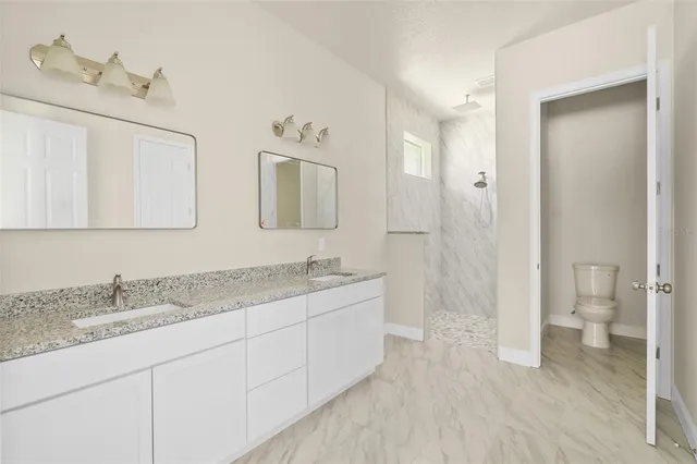 a bathroom with a granite countertop sink mirror and a toilet