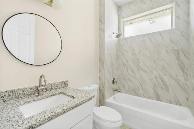 a bathroom with a granite countertop sink a toilet and a mirror