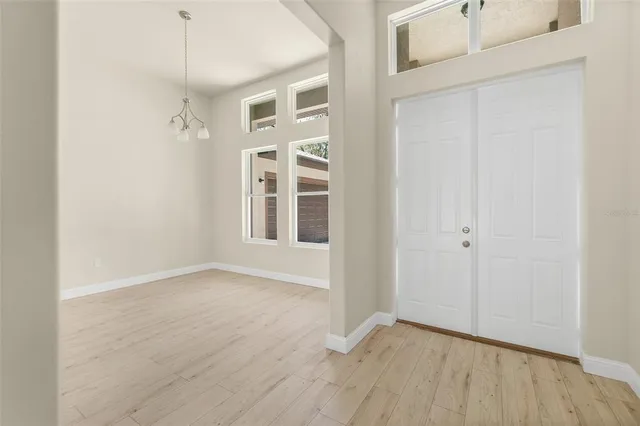 an empty room with wooden floor a ceiling fan and windows