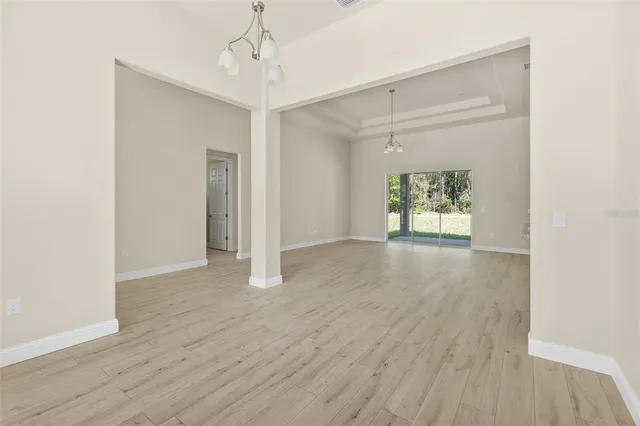 an empty room with wooden floor a ceiling fan and windows