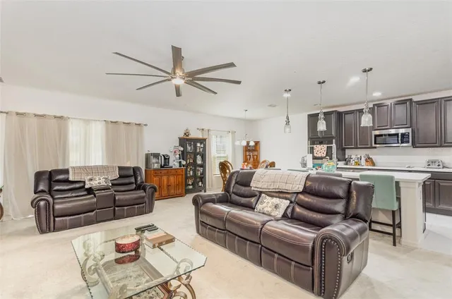 a living room with furniture kitchen view and a chandelier