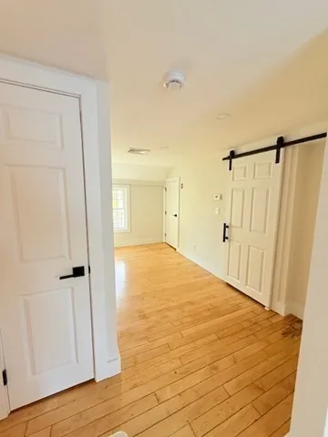 a view of an empty room with wooden floor and a window