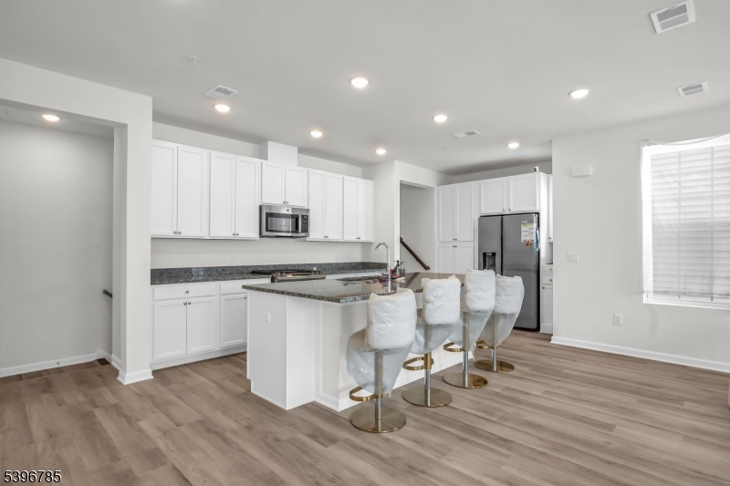 204 Honeysuckle Lane Warren, NJ 07059 - Photo 14 of 30 a kitchen with stainless steel appliances granite countertop a stove a sink a refrigerator and white cabinets with wooden floor