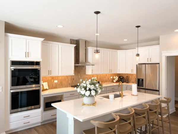 a kitchen with stainless steel appliances kitchen island granite countertop a refrigerator a stove a microwave oven a sink with a dining table and chairs