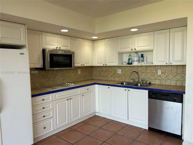 a kitchen with granite countertop white cabinets and stainless steel appliances
