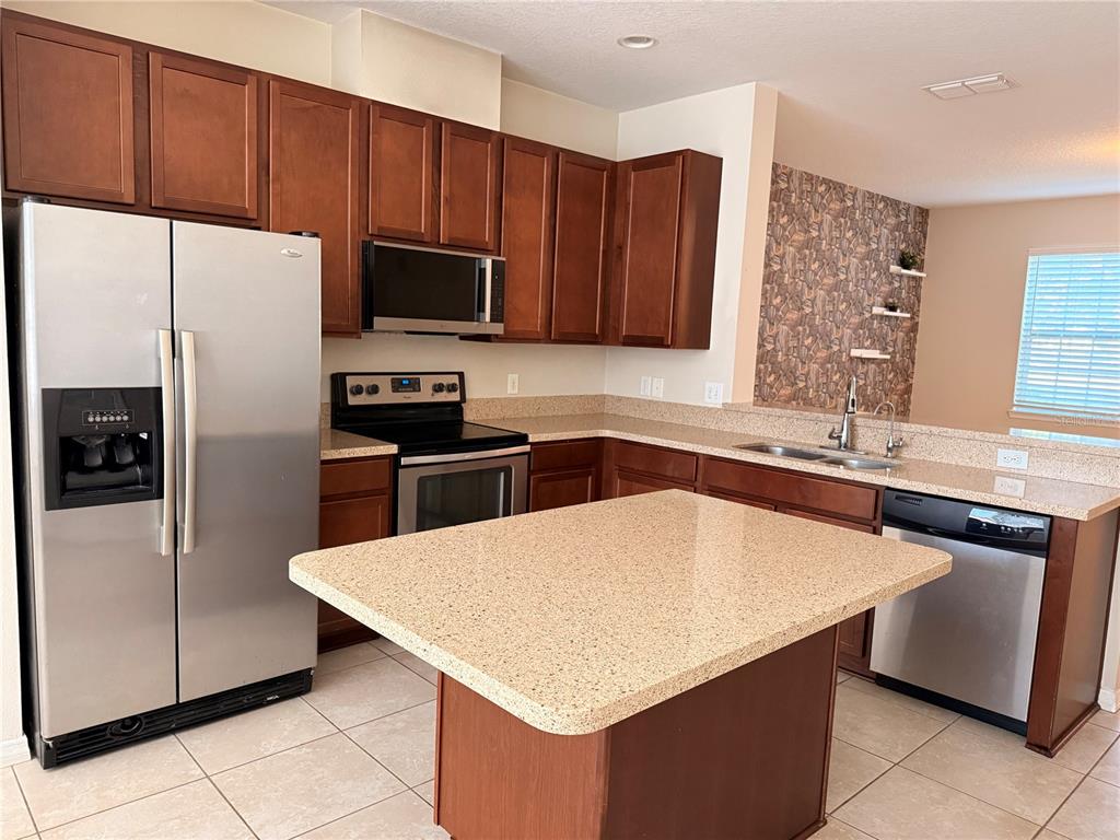 7843 Hardenton Street Windermere, FL 34786 - Photo 6 of 19 a kitchen with stainless steel appliances a refrigerator a sink a stove a microwave and wooden cabinets