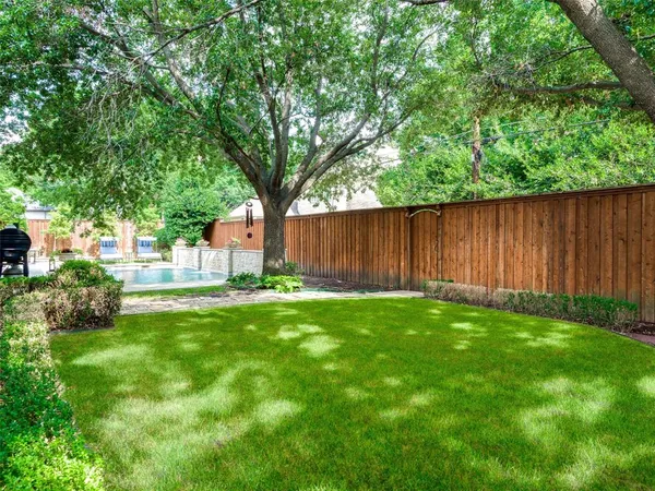 a view of backyard with large trees and wooden fence