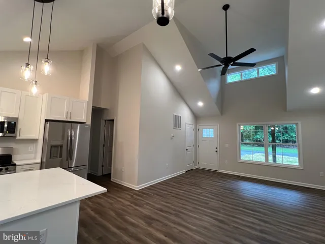 a kitchen with kitchen island a sink dishwasher stove and white cabinets with wooden floor