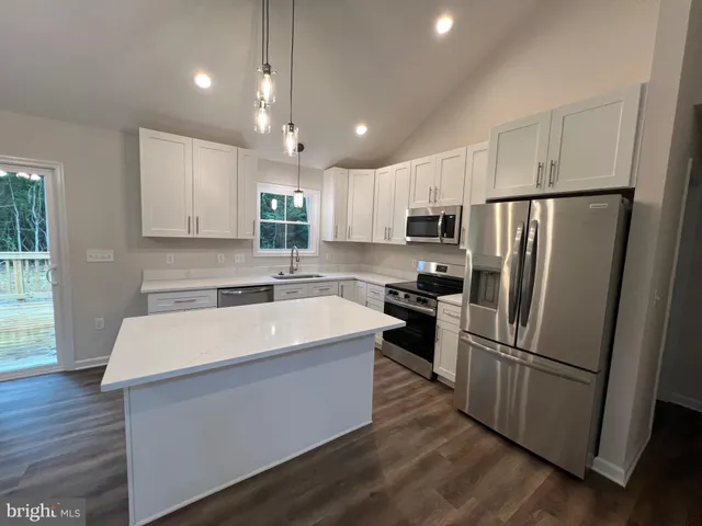 a kitchen with stainless steel appliances granite countertop a sink a stove and a wooden floors