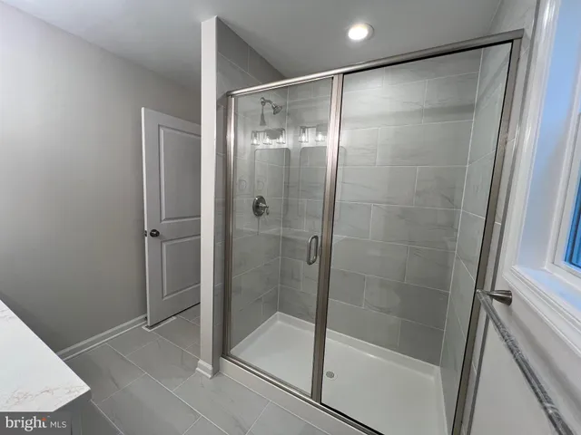 a view of an empty room with wooden floor and a ceiling fan