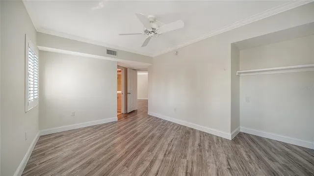 an empty room with wooden floor fan and windows